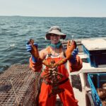 Person holding large lobster on fishing boat.