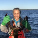 Person holding lobster on a boat.