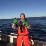 Person holding lobster on a boat.