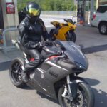 Motorcyclist in leather gear at gas station.